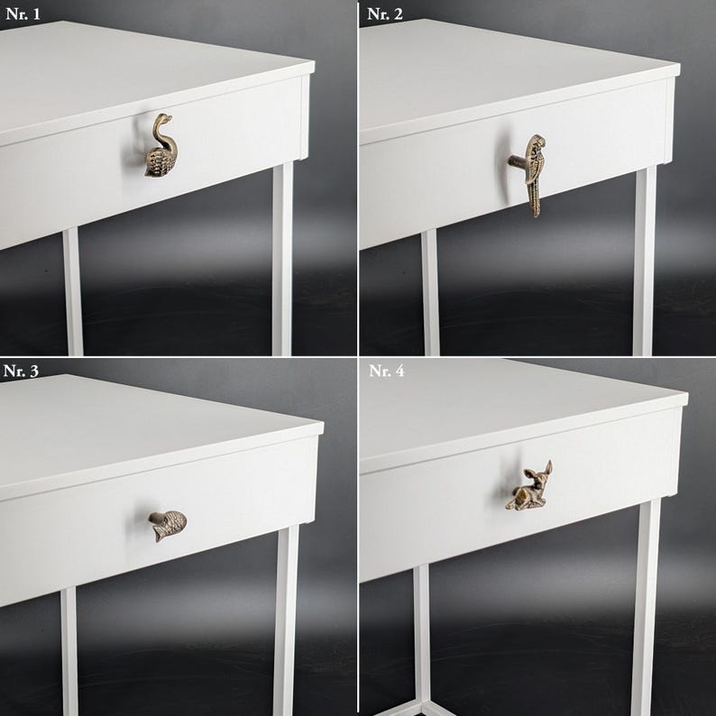 May include: Four white side tables with decorative drawer pulls. Each table has a different antique brass pull: a swan, a parrot, a leaf, and a deer. The tables have white legs and a white tabletop.