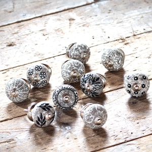 Pode incluir: Conjunto de 10 botões de armário de cerâmica com uma variedade de padrões em preto e branco. Os botões são redondos e têm um acabamento brilhante.