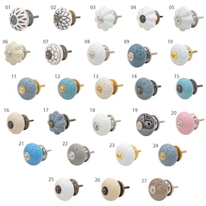 Op de afbeelding: Assortiment van 27 keramische kastknoppen in verschillende kleuren en patronen, waaronder wit, blauw, grijs, beige en roze. Elke knop heeft een uniek ontwerp en is versierd met een goudkleurige metalen basis.
