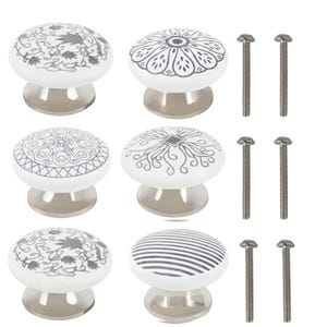 Può includere: Set di sei pomelli per armadi in ceramica bianca con base argentata e viti argentate. Ogni pomello presenta un diverso design geometrico in bianco e nero.