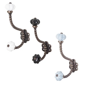 Könnte beinhalten: Drei antike Haken mit gedrehten Metallstielen und Keramikknöpfen. Die Knöpfe sind weiß, schwarz und hellblau.