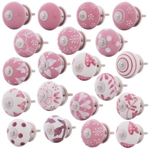 Könnte beinhalten: Eine Sammlung von neunzehn runden Schrankknöpfen mit verschiedenen rosa-weißen Mustern, darunter Punkte, Blumenmotive, Streifen und Herzdesigns. Jeder Knopf verfügt über einen silberfarbenen Metallsockel und eine zentrale Schraube.