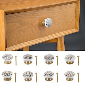 Op de afbeelding: Set van acht keramische ladeknopjes met verschillende geometrische en bloemmotieven in zwart, wit en goud. Elke knop heeft een messing basis en wordt geleverd met een schroef.