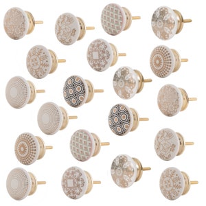 Op de afbeelding: Set van 18 keramische kastknoppen met gouden accenten. Elke knop heeft een ander geometrisch of bloemmotief.