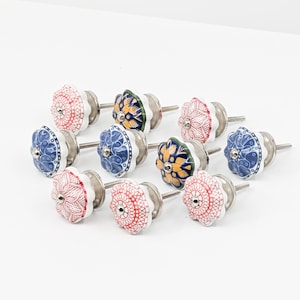 May include: Ten ceramic cabinet knobs with a white base and colorful floral designs. The knobs have a silver screw for attaching to a cabinet door.