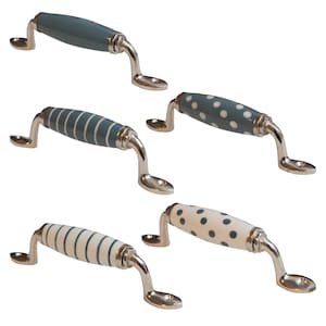 Könnte beinhalten: Fünf Keramik-Schrankknöpfe mit silbernem Metallfuß. Die Knöpfe haben ein blau-weiß gestreiftes Muster oder ein blau-weißes Punkte-Muster.
