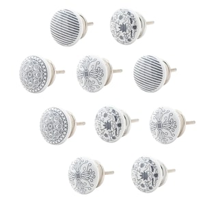 Könnte beinhalten: Satz von zehn weißen Keramik-Schrankknöpfen mit verschiedenen schwarzen und grauen Mustern. Die Knöpfe haben eine silberne Metallschraube.