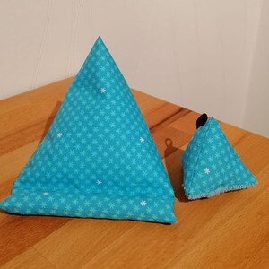 K&ouml;nnte beinhalten: Zwei blaue dreieckige Kissen mit einem wei&szlig;en Schneeflockenmuster. Das gr&ouml;&szlig;ere Kissen ist im Vordergrund und das kleinere Kissen im Hintergrund.
