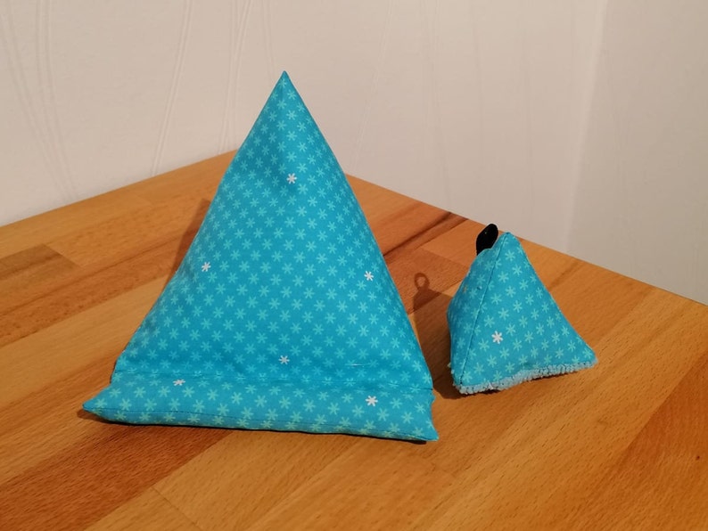 K&ouml;nnte beinhalten: Zwei blaue dreieckige Kissen mit einem wei&szlig;en Schneeflockenmuster. Das gr&ouml;&szlig;ere Kissen ist im Vordergrund und das kleinere Kissen im Hintergrund.