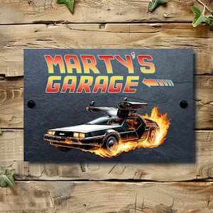 May include: A black slate sign with the text "Marty's Garage" in yellow and orange letters. A cartoon image of a DeLorean time machine with flames coming from the wheels is in the lower right corner of the sign.