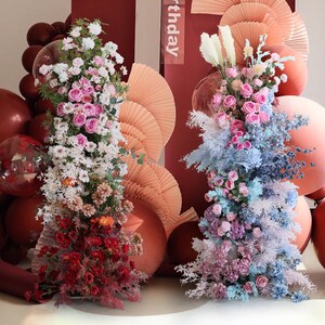 May include: Two floral arrangements with pink, white, and blue flowers, surrounded by peach and brown balloons. The text "birthday" is visible in the background.