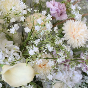 May include: A bouquet of white and cream flowers, including roses, carnations, and baby's breath. The flowers are arranged in a lush, romantic style.