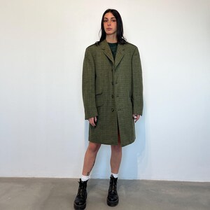 Puede incluir: Un abrigo largo de cuadros verdes con cierre de botones. El abrigo tiene cuello y lo lleva puesto una persona con el pelo negro y una camisa verde.