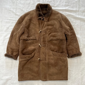 May include: A brown suede shearling coat with a fur collar and toggle closures. The coat has two large pockets on the front and a smaller pocket on the left side.