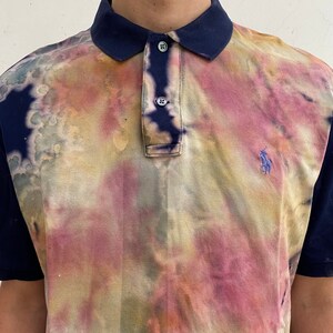 May include: A blue and white tie-dye polo shirt with a small embroidered logo on the right side of the chest.