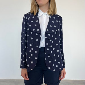 May include: A navy blue blazer with a white polka dot pattern. The blazer has a wide collar and a single button closure.
