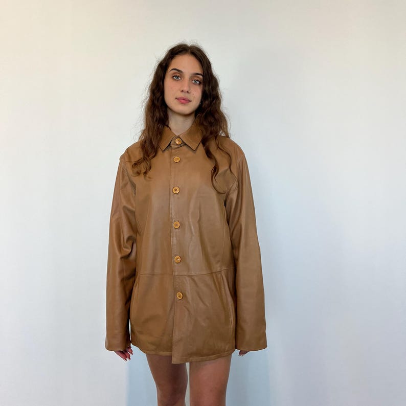 May include: A brown leather jacket with a button-up front and long sleeves.