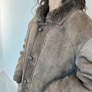 Puede incluir: Una chaqueta de ante marr&oacute;n con cuello de piel sint&eacute;tica. La chaqueta tiene cierre de botones y un bolsillo de parche en el lado izquierdo.