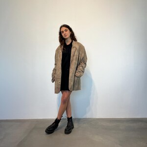 May include: A person wearing a brown suede jacket with a black shirt and black boots.