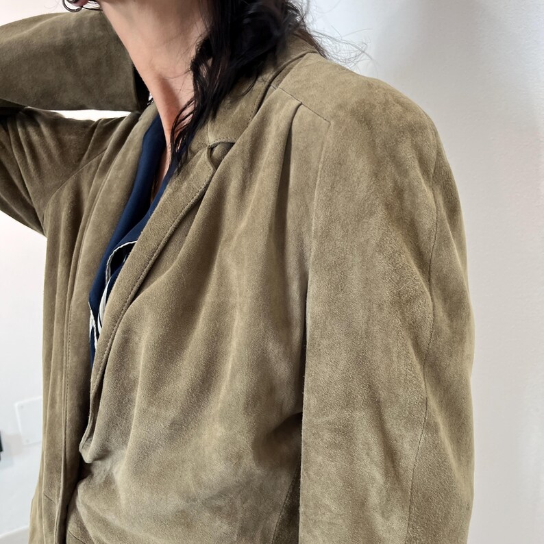 May include: A brown suede jacket with a long sleeve and a collar.
