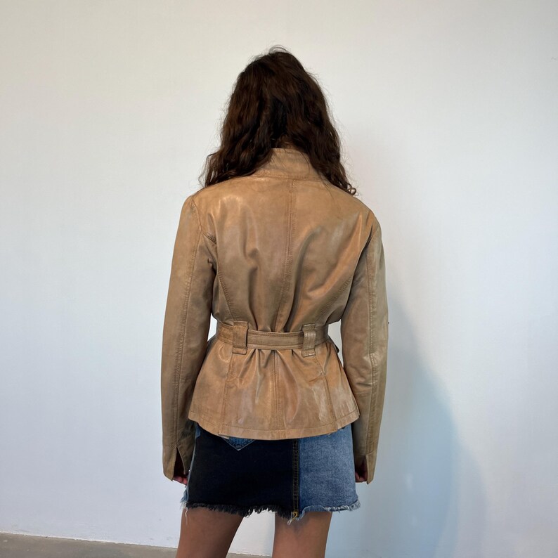 K&ouml;nnte beinhalten: Eine braune Lederjacke mit G&uuml;rtelbund. Die Jacke hat eine leicht taillierte Silhouette und lange &Auml;rmel.