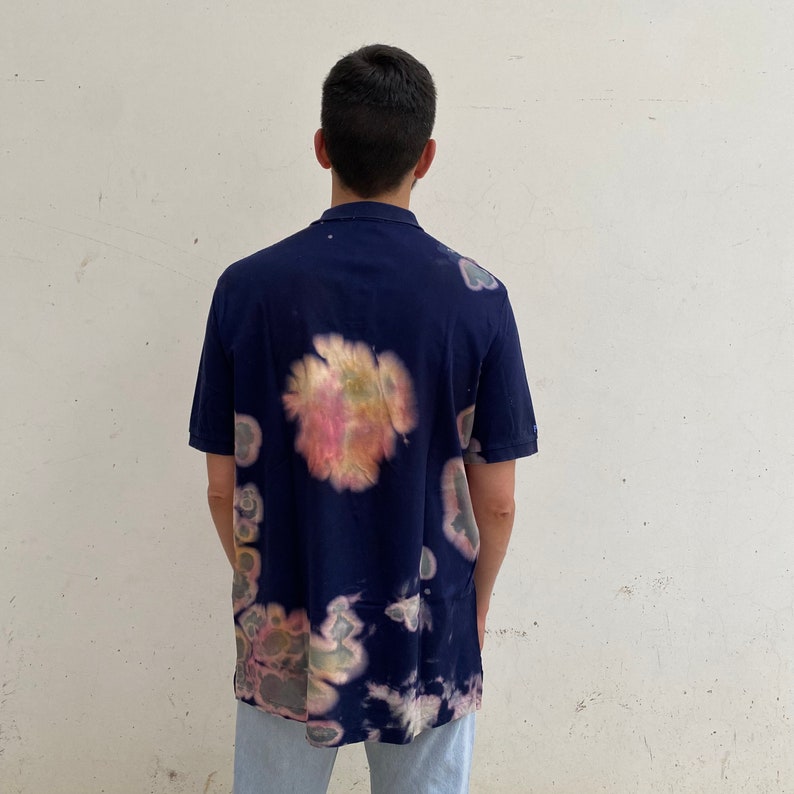 May include: A navy blue short-sleeved shirt with a tie-dye pattern in shades of pink, yellow, and green.