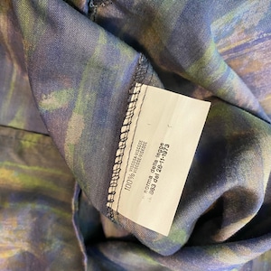 May include: A white tag with black text on a dark blue and green fabric. The tag reads "VISCOSA-VISCOSE 100% VISCOSE-VISKOSE norma della legge 883 del 26-11-1973".