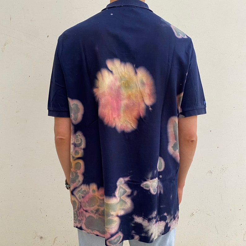May include: A navy blue short-sleeved polo shirt with a tie-dye pattern in shades of pink, yellow, and green.