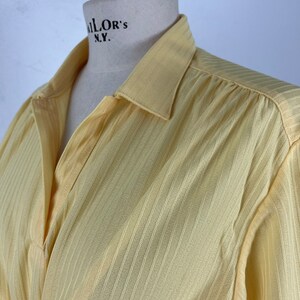 May include: A yellow collared shirt with vertical stripes. The shirt has a button closure and long sleeves.