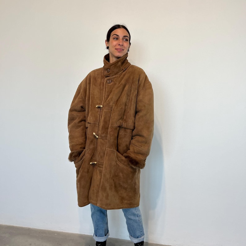 May include: A brown suede long coat with a fur-lined collar and wooden toggle closures.