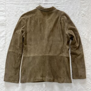 May include: A brown suede jacket with a long sleeve and a button-up collar.