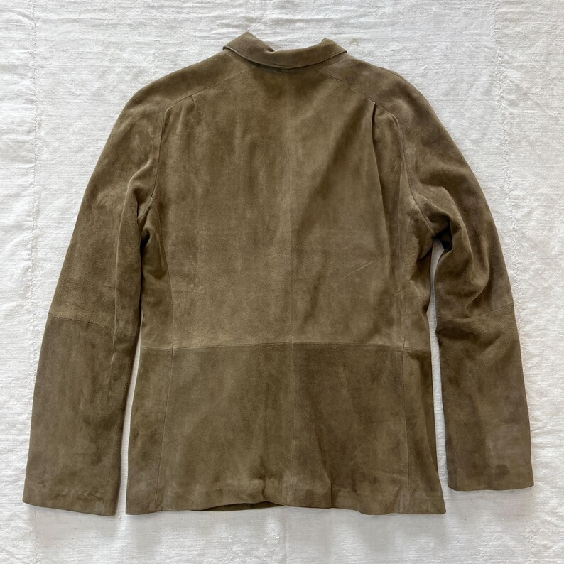 May include: A brown suede jacket with a long sleeve and a button-up collar.