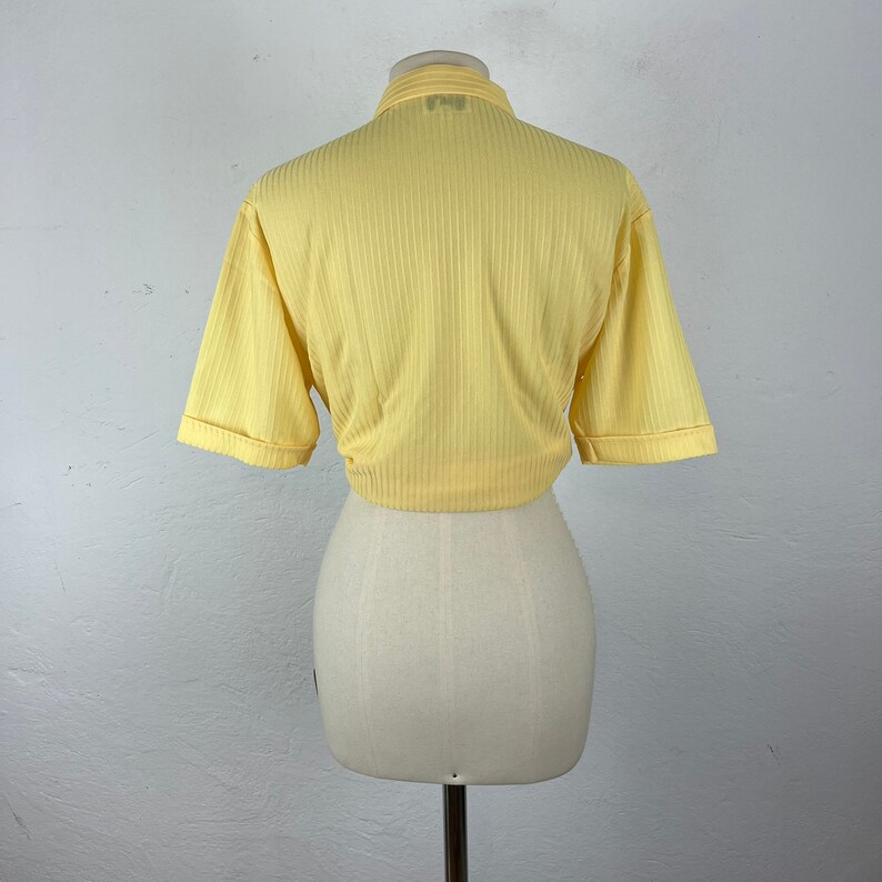 May include: A yellow ribbed short-sleeved crop top with a collared neckline.