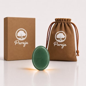 Può includere: Una pietra verde liscia di forma ovale posizionata davanti a una scatola di cartone marrone e a un sacchetto marrone con coulisse. Sia la scatola che il sacchetto presentano un logo circolare bianco con un albero e il testo Puraja stampato.