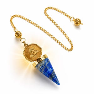 May include: A cone-shaped lapis lazuli pendulum with a gold-toned metal cap featuring an embossed eye within a triangle. The pendulum hangs from a gold-toned chain with a decorative filigree bead at the end, creating a radiant light effect.