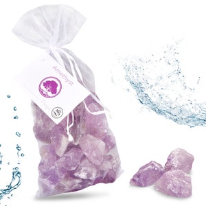 Könnte beinhalten: Ein weißer Organzasack gefüllt mit Amethyst-Kristallen. Der Beutel trägt ein Etikett mit der Aufschrift "Amethyst". Es befinden sich auch ein paar Amethyst-Kristalle außerhalb des Beutels.