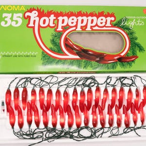 May include: Vintage NOMA 35 hot pepper lights in a box. The box is green with red text and a graphic of red chili peppers. The lights are red chili pepper shaped and strung on a green wire.