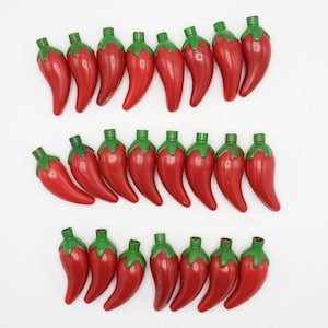 May include: Rows of red chili pepper-shaped objects with green tops are arranged on a white background. The peppers have a glossy finish and are evenly spaced. The image showcases a collection of decorative items.