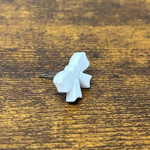 May include: A white bow-shaped earring with a silver post.