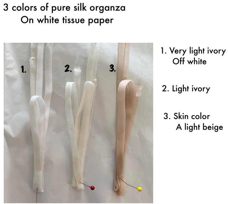 May include: Three samples of pure silk organza fabric in different shades of ivory, displayed on white tissue paper. The fabric is labeled 1. Very light ivory Off white, 2. Light ivory, and 3. Skin color A light beige.