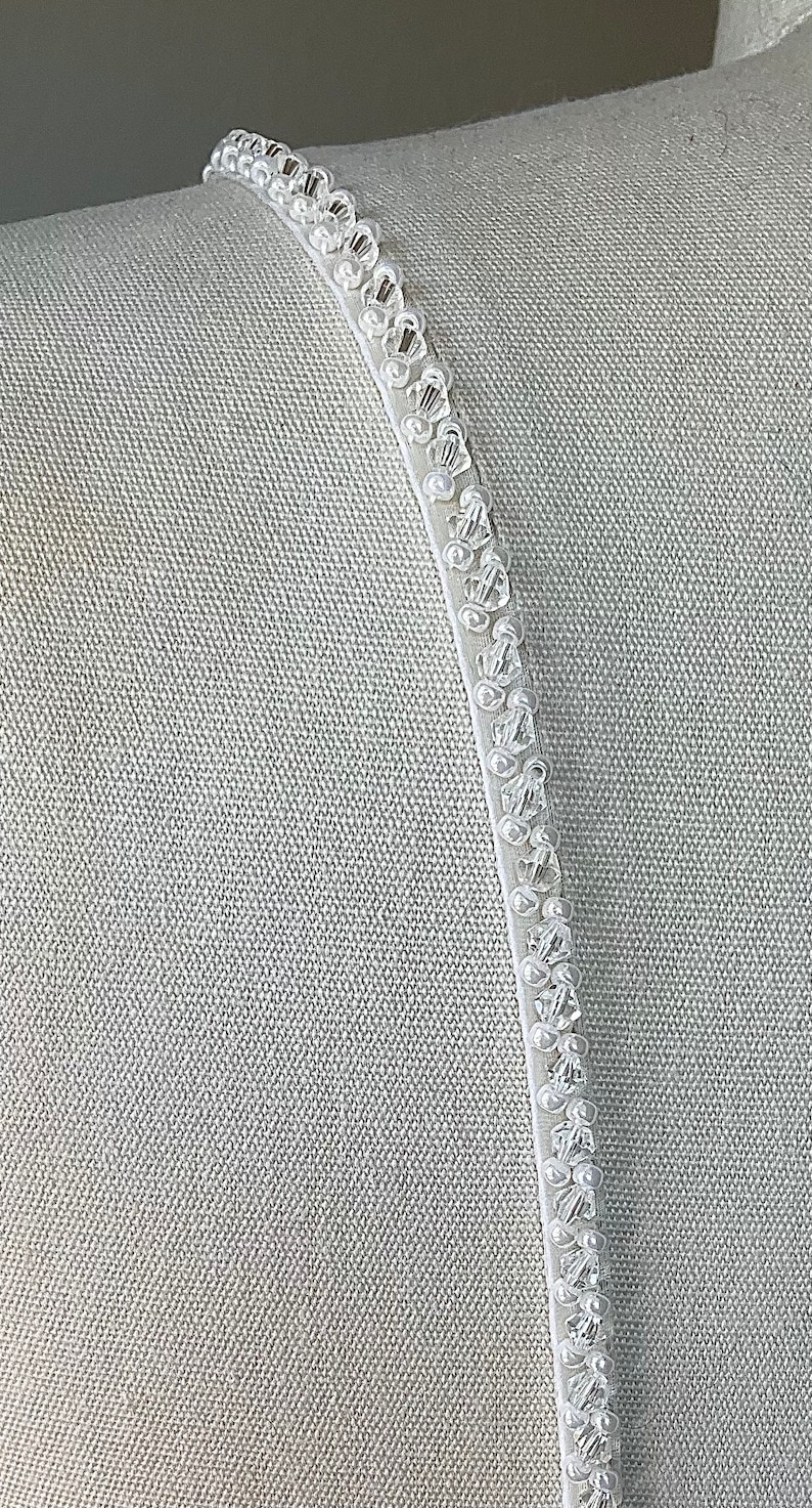 May include: White beaded trim with small, clear beads sewn onto a white fabric background.