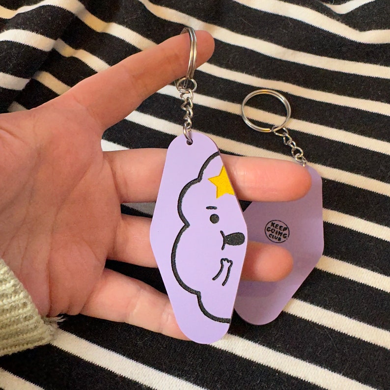 May include: Purple and light blue keychains with a cartoon character and the text "Keep Going Club".