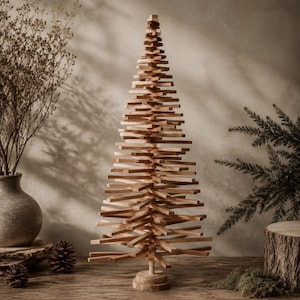 May include: A decorative Christmas tree sculpture constructed from numerous horizontal light brown wooden slats stacked around a central vertical dowel, featuring a conical shape and a circular wooden base, standing on a flat surface.