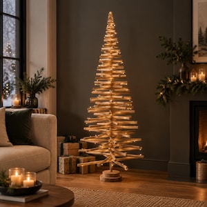 Könnte beinhalten: Ein hoher, konischer Weihnachtsbaum aus gestapelten, horizontalen hellbraunen Holzästen. Die Struktur steht auf einem runden Holzsockel und wird von dünnen, warm leuchtenden Lichterketten erhellt, die um die Äste gewickelt sind.