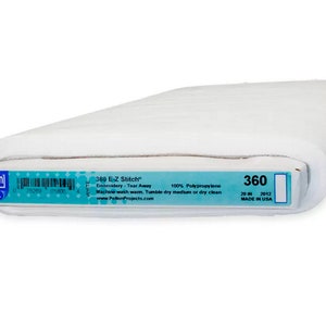 May include: A roll of white Pellon 360 E-Z Stitch embroidery tear-away fabric. The label indicates it is 50.8 cm wide and made of 100% polypropylene. The label also includes the text "Machine wash warm. Tumble dry medium or dry clean."