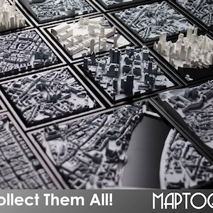 May include: A collection of framed 3D printed cityscapes in black frames. The text "Collect Them All!" and "MAPTOGRAM" are visible at the bottom of the image.