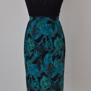 May include: A teal and black skirt with a floral print. The skirt is knee-length and has a fitted silhouette.