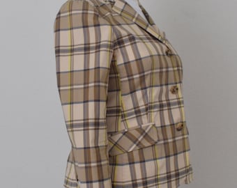May include: A tan, brown, yellow, and blue plaid blazer with two front pockets and three brown buttons. The blazer is displayed on a white mannequin and is paired with white pants.