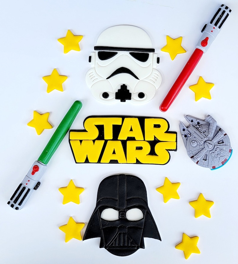 A Star Wars cake kit including 2 light sabers, Millennium Falcon, Darth Vader head, Storm Trooper head, Star Wars Logo, and 10 small stars