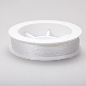 May include: A white spool of thread in a white plastic container.